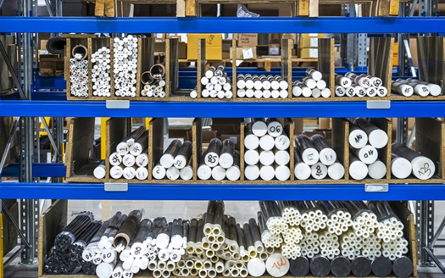 Plast- ja komposiitmaterjalist vardad ja torud ladustatud riiulitele tööstuslaos.